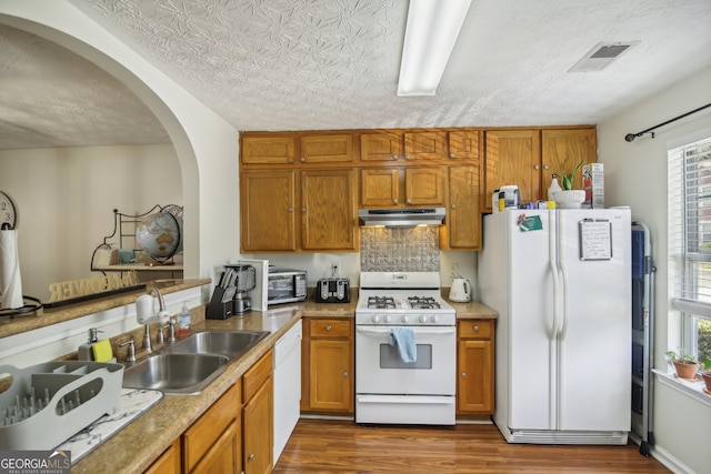 kitchen featuring a textured ceiling, dark hardwood / wood-style floors, white appliances, sink, and backsplash