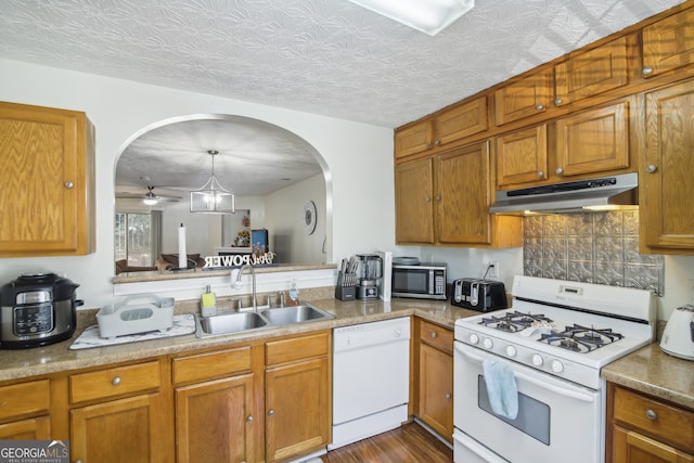 kitchen with dark hardwood / wood-style floors, white appliances, sink, pendant lighting, and a textured ceiling