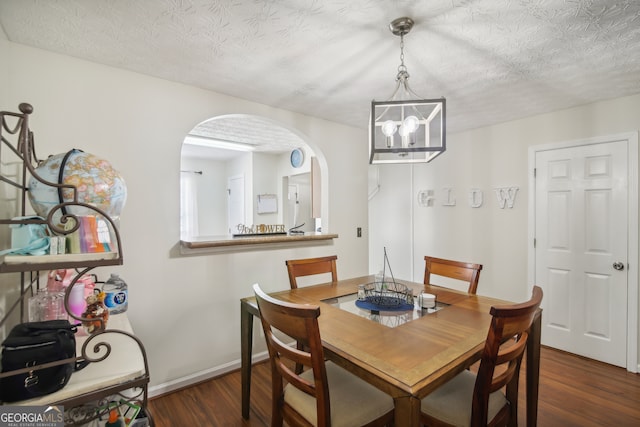 dining area featuring a textured ceiling, dark hardwood / wood-style floors, and a chandelier