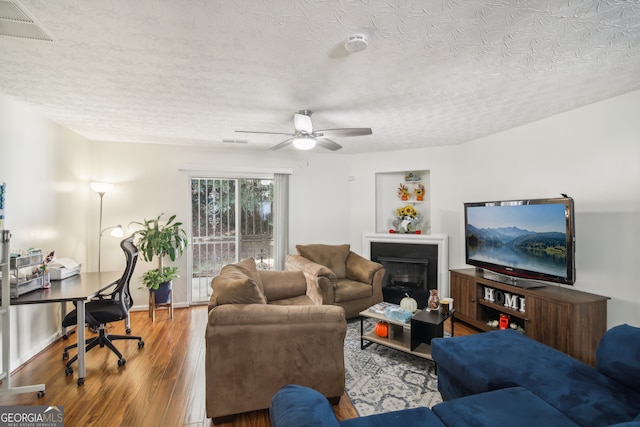 living room with ceiling fan, wood-type flooring, and a textured ceiling