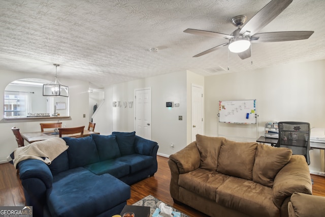 living room featuring a textured ceiling, ceiling fan with notable chandelier, and dark hardwood / wood-style flooring