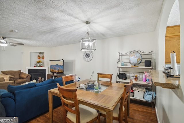 dining area with ceiling fan with notable chandelier, dark hardwood / wood-style flooring, and a textured ceiling