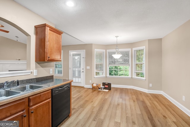 kitchen featuring pendant lighting, dishwasher, sink, light wood-type flooring, and a textured ceiling