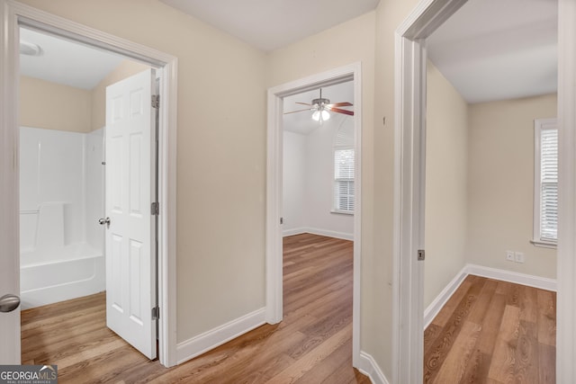 hallway featuring vaulted ceiling and light hardwood / wood-style flooring