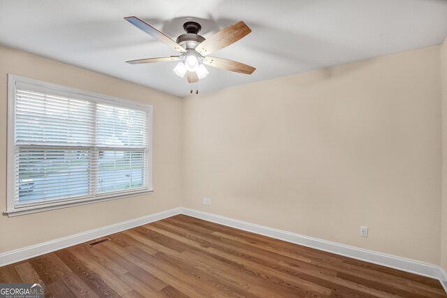 empty room with ceiling fan and dark hardwood / wood-style flooring