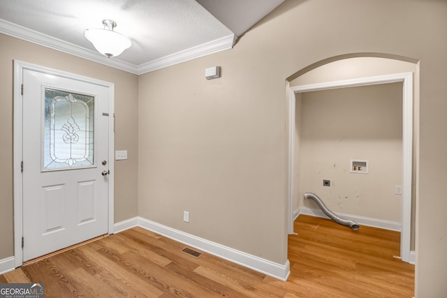 foyer entrance featuring light hardwood / wood-style floors, ornamental molding, and a textured ceiling