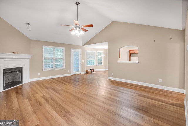 unfurnished living room featuring ceiling fan, a healthy amount of sunlight, vaulted ceiling, and light wood-type flooring