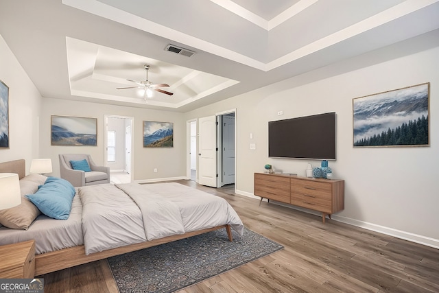 bedroom featuring wood-type flooring, a raised ceiling, and ceiling fan