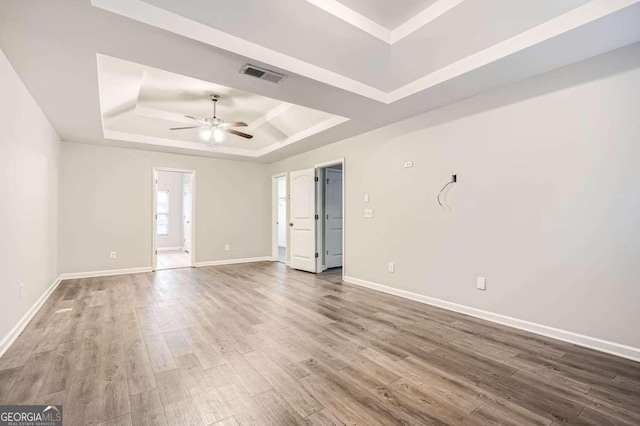 unfurnished room featuring a tray ceiling, ceiling fan, and hardwood / wood-style flooring