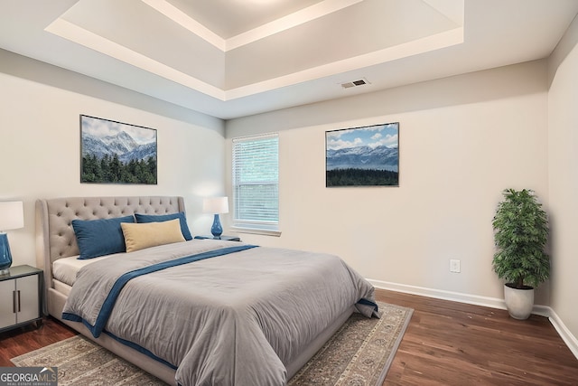 bedroom with a raised ceiling and dark hardwood / wood-style flooring