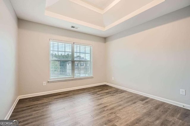 spare room featuring dark hardwood / wood-style floors and a tray ceiling