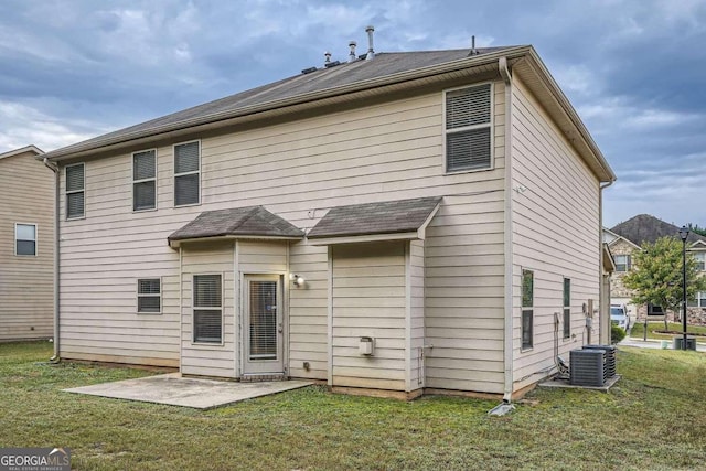 rear view of property with a yard, a patio, and central air condition unit