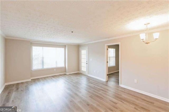 spare room featuring an inviting chandelier, ornamental molding, a textured ceiling, and light hardwood / wood-style floors