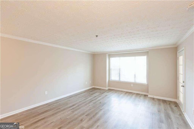 empty room with a textured ceiling, light wood-type flooring, and ornamental molding