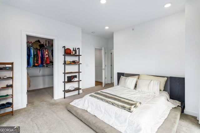 bedroom featuring light colored carpet, a closet, and a walk in closet