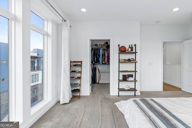 bedroom featuring light carpet, a closet, and a walk in closet