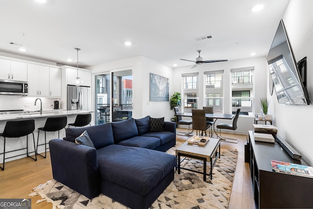 living room featuring sink, light hardwood / wood-style flooring, and ceiling fan