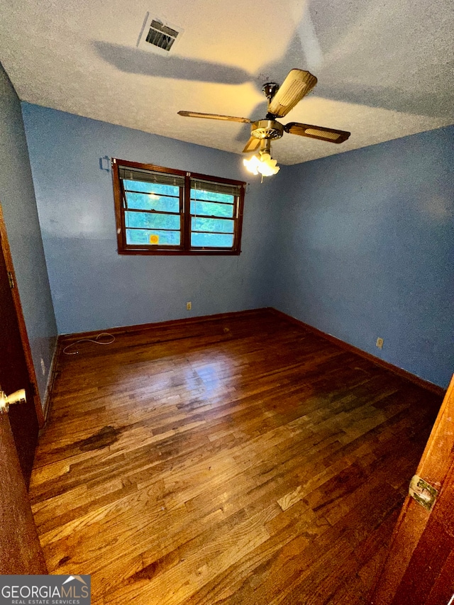 empty room featuring wood-type flooring, a textured ceiling, lofted ceiling, and ceiling fan