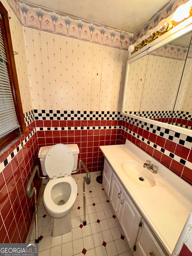 bathroom with vanity, tile walls, tile patterned floors, toilet, and a textured ceiling