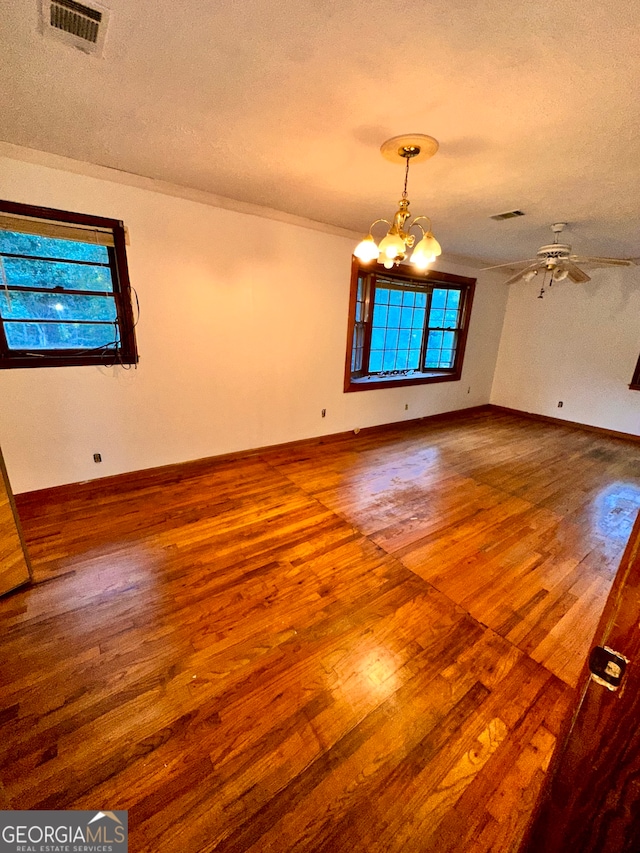 unfurnished room with wood-type flooring, a textured ceiling, and ceiling fan with notable chandelier