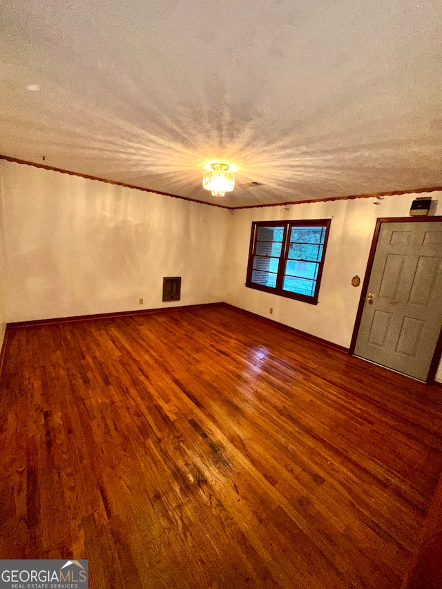 unfurnished room with hardwood / wood-style flooring and a textured ceiling