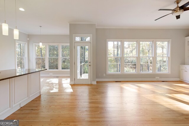 unfurnished living room featuring ceiling fan, light wood-type flooring, and ornamental molding