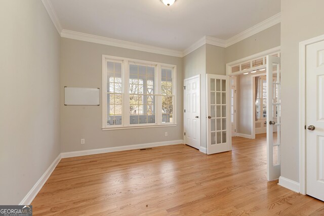 empty room featuring french doors, light hardwood / wood-style floors, and ornamental molding