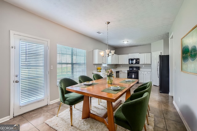 tiled dining room featuring a textured ceiling and an inviting chandelier