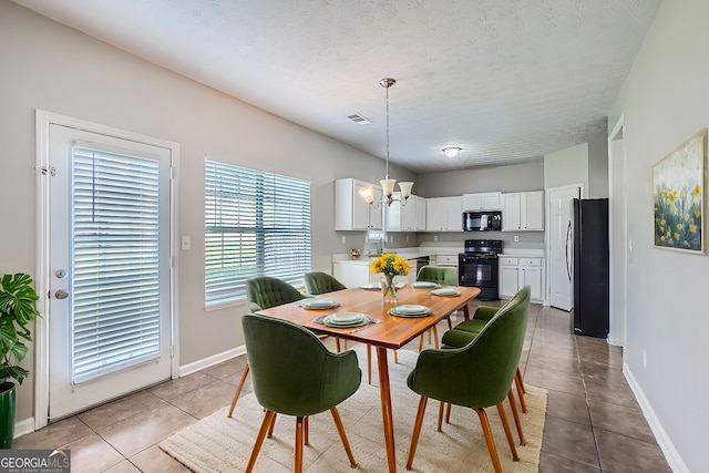 dining area featuring light tile patterned floors, a textured ceiling, and an inviting chandelier