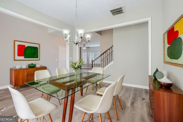 dining space with light hardwood / wood-style floors and a chandelier