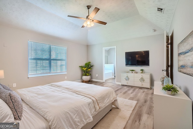 bedroom featuring ensuite bath, ceiling fan, light hardwood / wood-style flooring, a textured ceiling, and vaulted ceiling