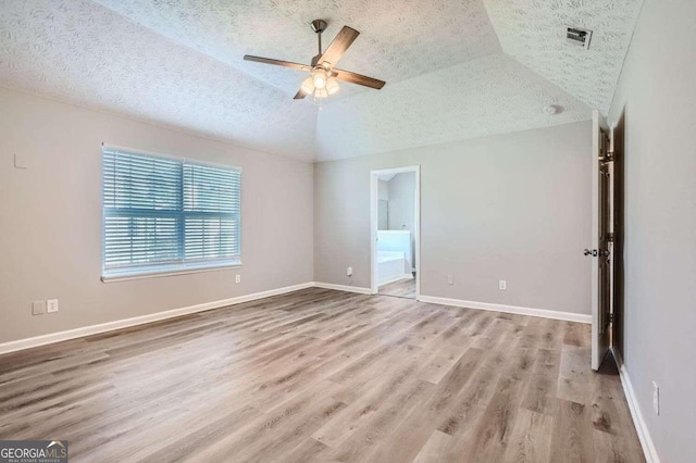 empty room with ceiling fan, light wood-type flooring, a textured ceiling, and vaulted ceiling