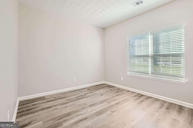 unfurnished room featuring light hardwood / wood-style floors and a textured ceiling