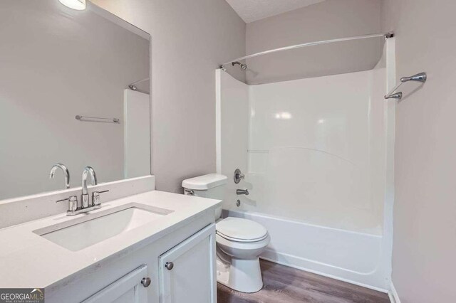 full bathroom featuring vanity, hardwood / wood-style floors, a textured ceiling, toilet, and shower / bathing tub combination