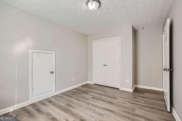 unfurnished bedroom with a textured ceiling, hardwood / wood-style flooring, and a closet