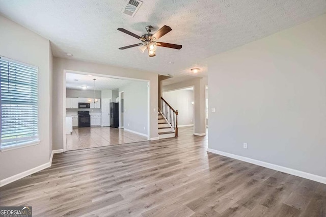 unfurnished living room featuring wood-type flooring, a textured ceiling, and ceiling fan