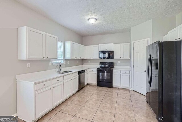 kitchen with white cabinetry, sink, light tile patterned flooring, and black appliances