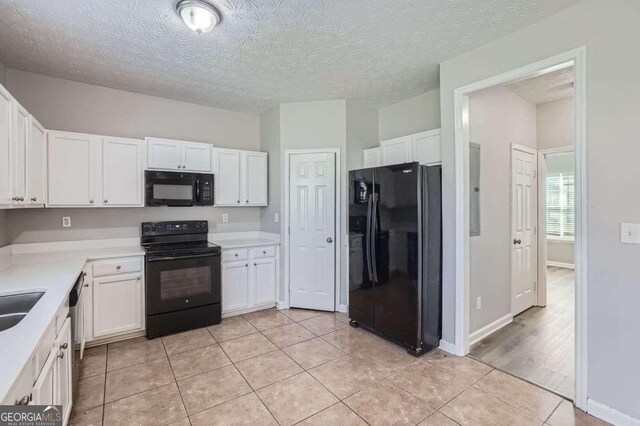 kitchen featuring white cabinets, a textured ceiling, light tile patterned flooring, and black appliances