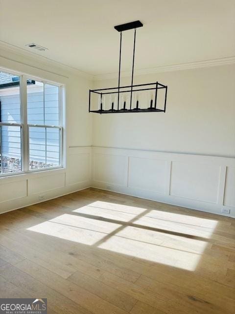 unfurnished dining area featuring crown molding and light wood-type flooring