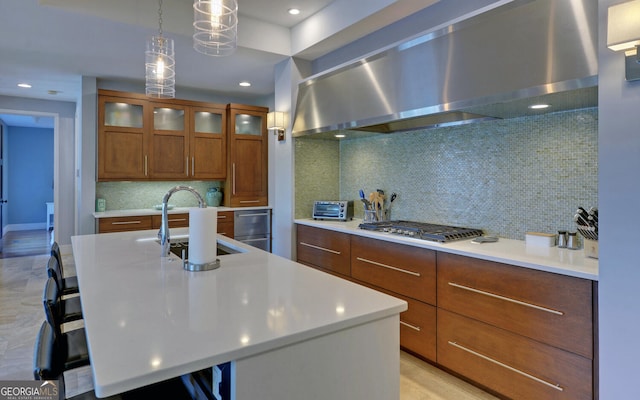 kitchen with wall chimney exhaust hood, a center island with sink, tasteful backsplash, and a breakfast bar