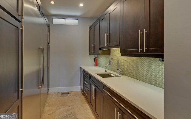 kitchen featuring backsplash, sink, dark brown cabinetry, and high end fridge