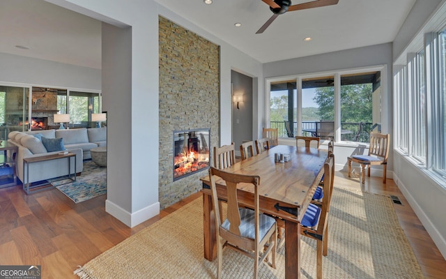 dining area featuring a fireplace, hardwood / wood-style flooring, and ceiling fan