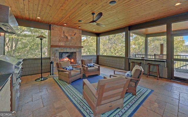 sunroom / solarium featuring a fireplace, wood ceiling, and plenty of natural light