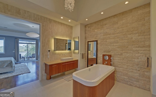 bathroom featuring wood-type flooring, vanity, a bathtub, and tile walls