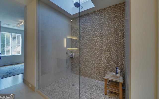 bathroom with tile walls, tile patterned flooring, tiled shower, and a skylight