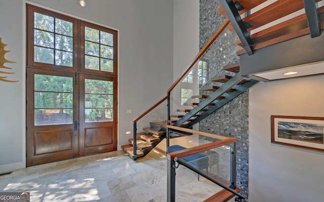 foyer entrance featuring beam ceiling, french doors, and a towering ceiling