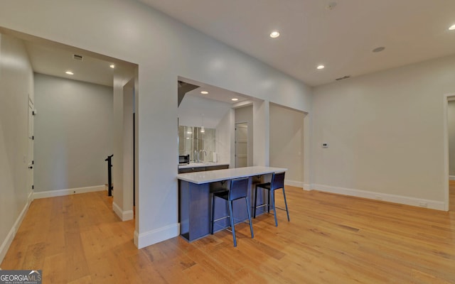 kitchen with a kitchen bar and light hardwood / wood-style flooring