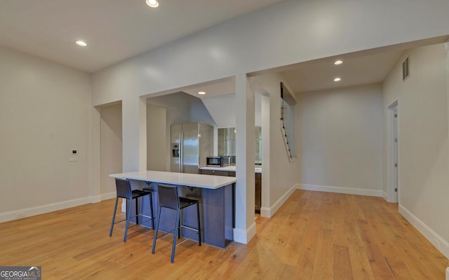 kitchen featuring light hardwood / wood-style floors, a breakfast bar area, and appliances with stainless steel finishes