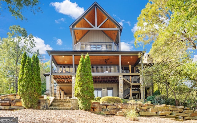 back of property with ceiling fan and a balcony