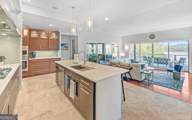 kitchen featuring a center island with sink, backsplash, hanging light fixtures, sink, and a kitchen breakfast bar